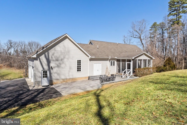 rear view of house featuring a yard, a patio, roof with shingles, and a sunroom