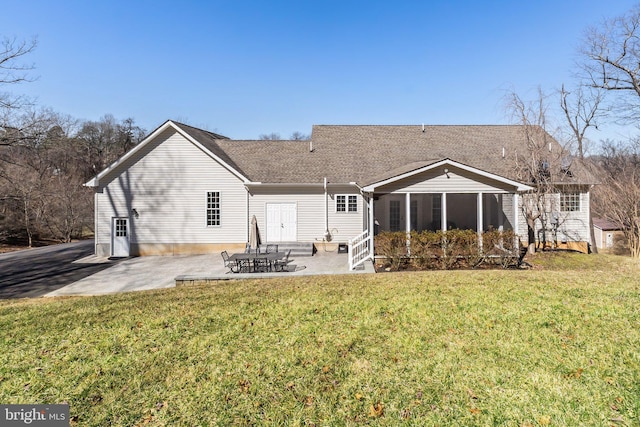 back of house featuring a patio, a lawn, roof with shingles, and a sunroom