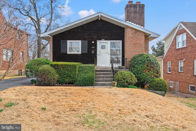 view of front of house featuring a front lawn, brick siding, and a chimney