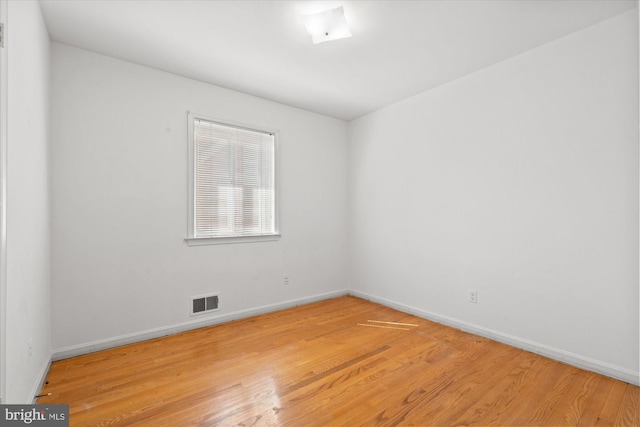 empty room featuring visible vents, baseboards, and wood finished floors