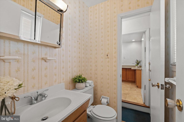 bathroom with wallpapered walls, toilet, and vanity