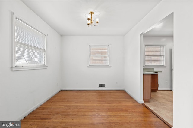 unfurnished dining area featuring light wood-style floors, visible vents, and a wealth of natural light