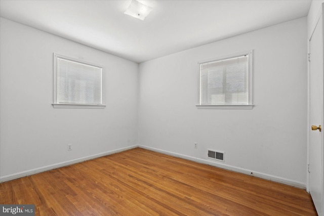 spare room featuring visible vents, baseboards, and wood finished floors