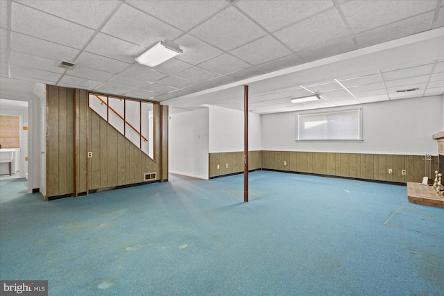 below grade area with a wainscoted wall, wood walls, a paneled ceiling, and visible vents