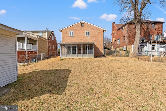 rear view of property with a lawn, a fenced backyard, and a sunroom