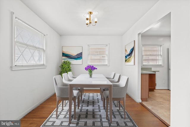 dining area featuring an inviting chandelier, wood finished floors, and baseboards