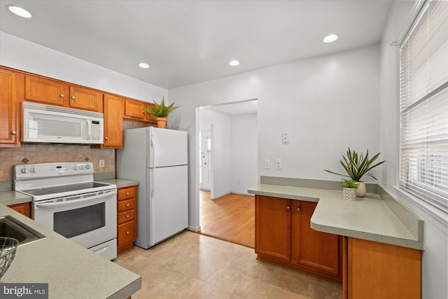 kitchen featuring tasteful backsplash, brown cabinets, white appliances, and light countertops