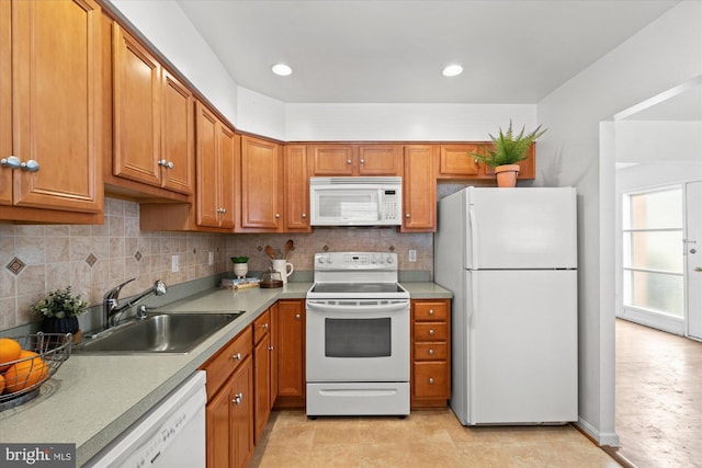 kitchen with decorative backsplash, white appliances, brown cabinetry, and a sink