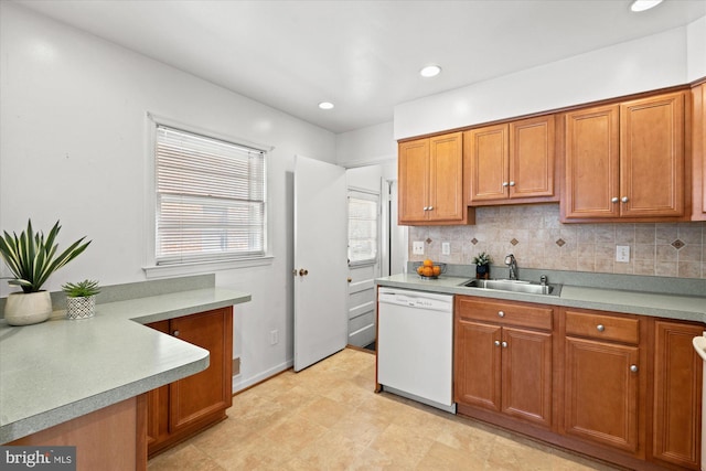 kitchen featuring brown cabinetry, backsplash, dishwasher, and a sink