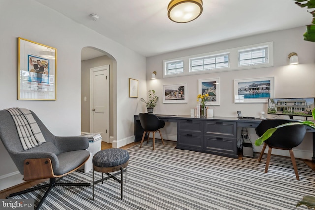 living area with arched walkways, an office area, baseboards, and plenty of natural light