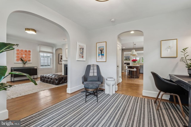 sitting room featuring wood finished floors, baseboards, and arched walkways