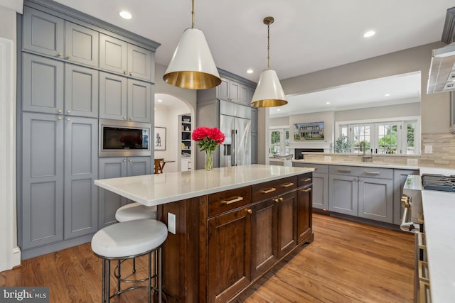 kitchen featuring high end appliances, gray cabinets, light countertops, light wood-style flooring, and recessed lighting