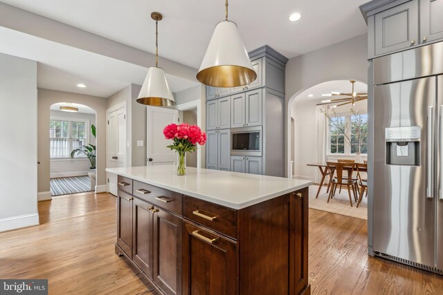 kitchen with stainless steel appliances, arched walkways, light wood-style flooring, and recessed lighting