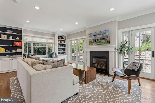 living area featuring light wood-style floors, recessed lighting, a fireplace with flush hearth, built in features, and crown molding