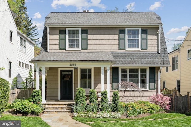 view of front of home with roof with shingles, fence, and covered porch