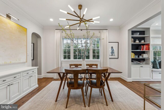 dining room featuring a chandelier, wood finished floors, arched walkways, crown molding, and baseboards