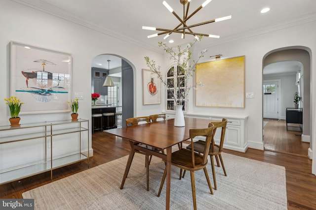 dining room with arched walkways, wood finished floors, crown molding, a chandelier, and healthy amount of natural light