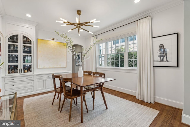 dining space featuring baseboards, ornamental molding, wood finished floors, arched walkways, and recessed lighting