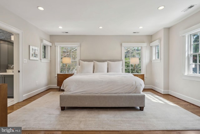 bedroom with wood finished floors, recessed lighting, baseboards, and a sink