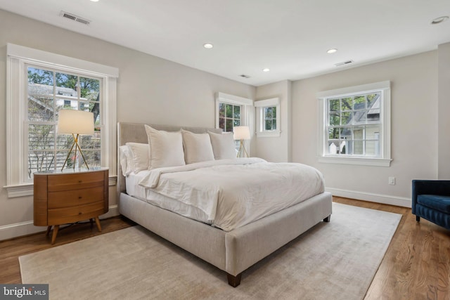 bedroom with multiple windows, wood finished floors, and recessed lighting