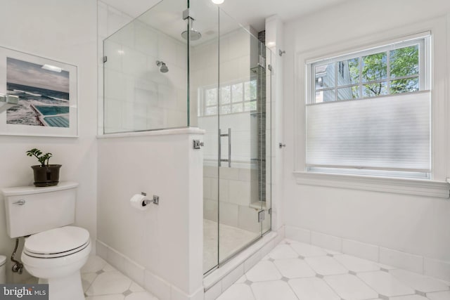 full bathroom with toilet, a shower stall, and baseboards