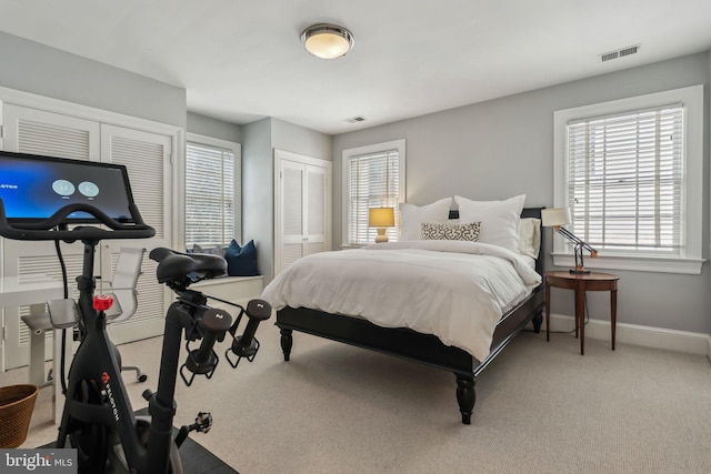 bedroom featuring multiple windows, baseboards, and light colored carpet