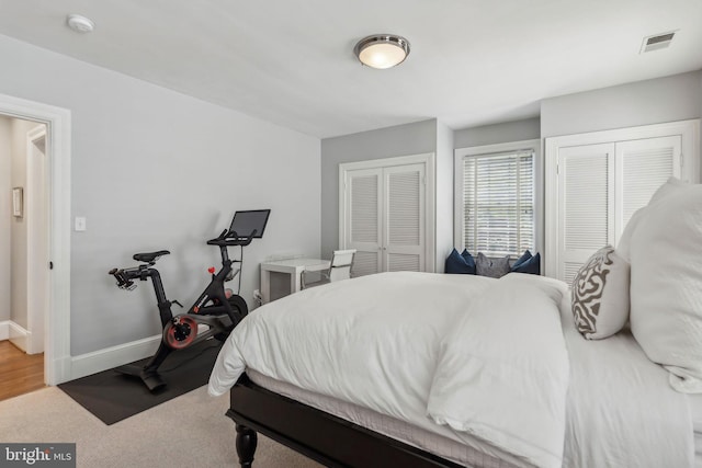 bedroom with two closets, baseboards, and carpet floors