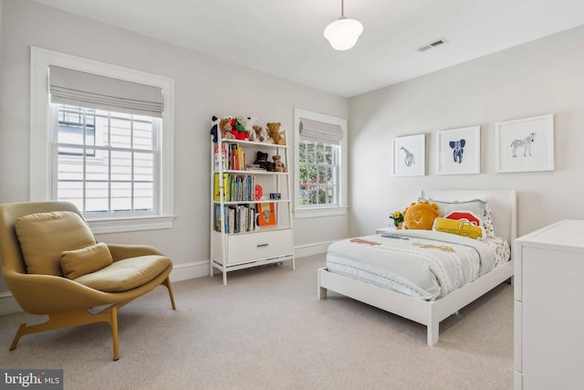 bedroom featuring multiple windows, light colored carpet, and baseboards