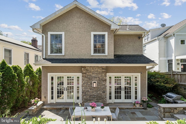 rear view of house with french doors, stucco siding, a patio area, and stone siding