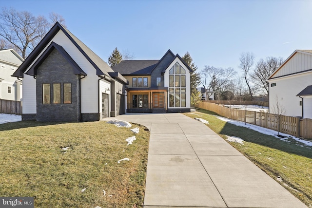 view of front facade with a garage, concrete driveway, a front yard, and fence