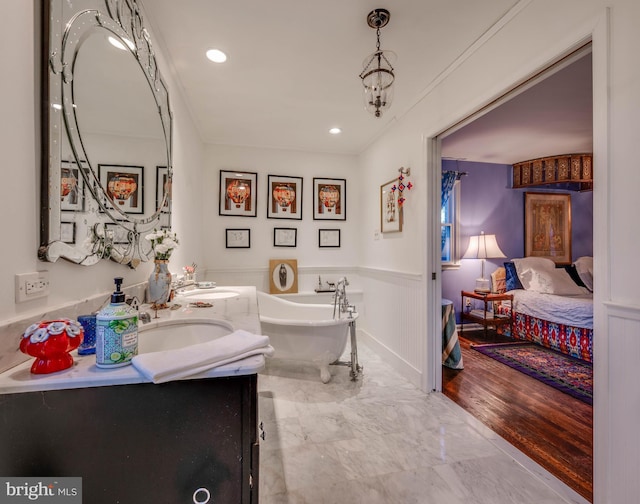 bathroom featuring double vanity, a freestanding tub, marble finish floor, and a sink