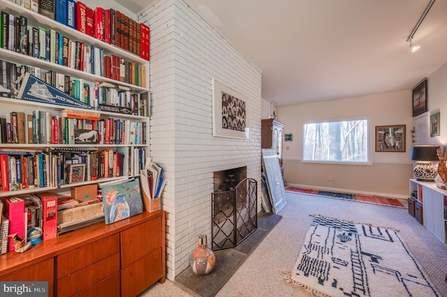 sitting room featuring track lighting, a brick fireplace, and baseboards