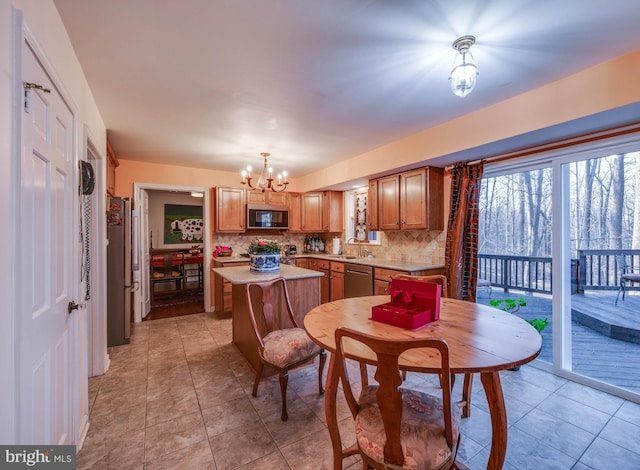 kitchen featuring a notable chandelier, a kitchen island, stainless steel appliances, light countertops, and decorative backsplash