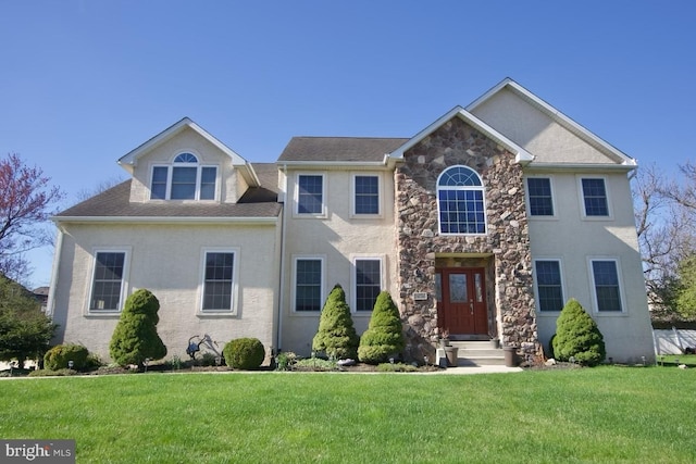 colonial house with a front yard, stone siding, and stucco siding