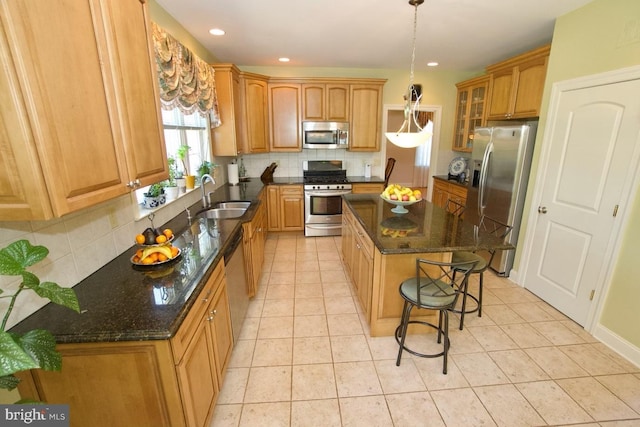 kitchen with a kitchen island, a breakfast bar, decorative backsplash, stainless steel appliances, and a sink