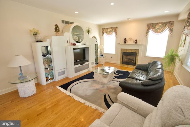 living area with visible vents, baseboards, wood finished floors, and a tile fireplace