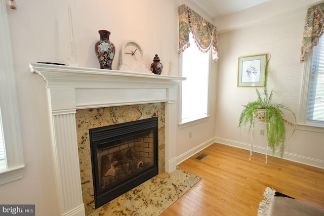 interior details with a high end fireplace, visible vents, baseboards, and wood finished floors