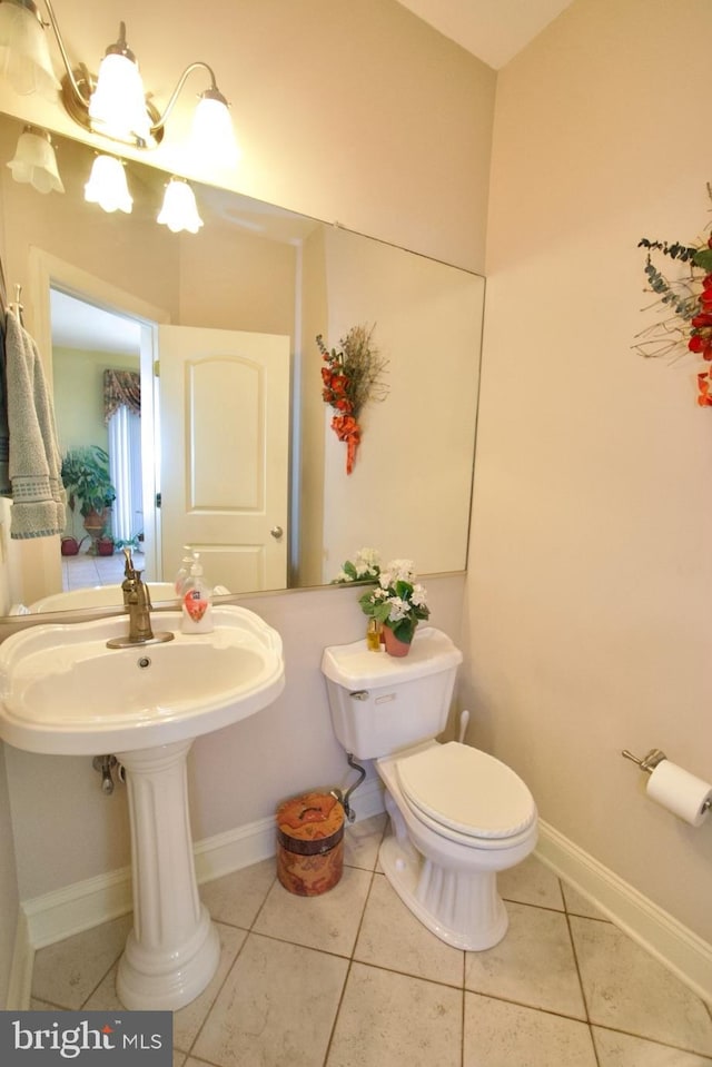 half bathroom featuring tile patterned flooring, toilet, and baseboards