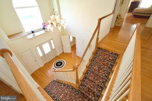 entryway with a notable chandelier, stairway, light wood-type flooring, and a towering ceiling