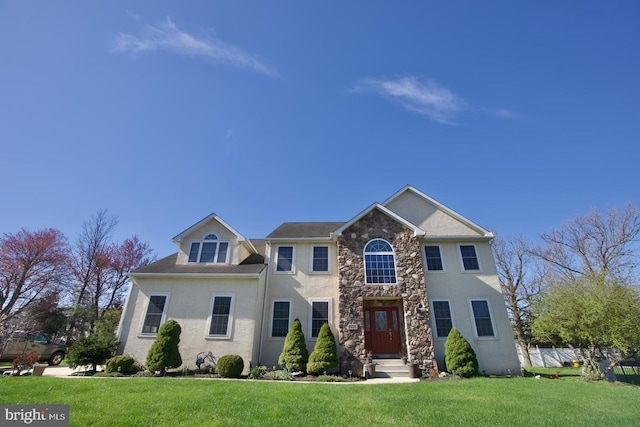 colonial house featuring stucco siding, stone siding, and a front lawn