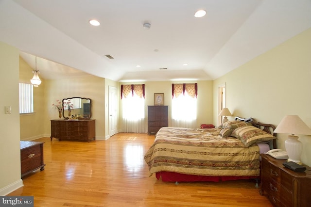 bedroom featuring visible vents, a raised ceiling, recessed lighting, light wood-style floors, and baseboards