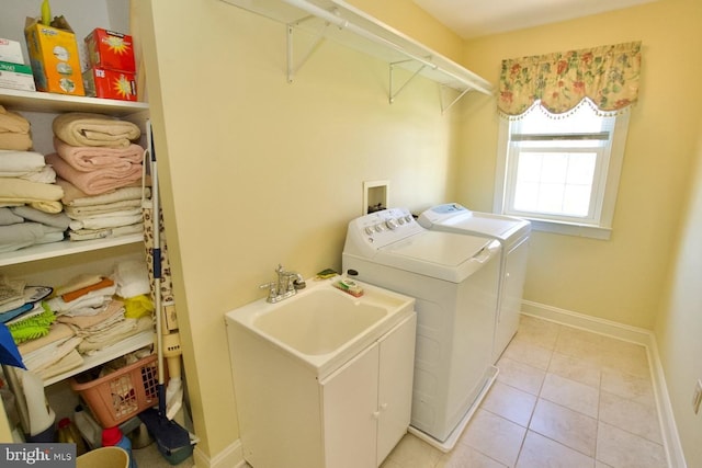 laundry area featuring baseboards, washing machine and dryer, light tile patterned floors, laundry area, and a sink