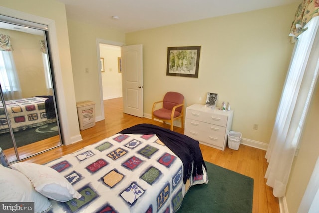 bedroom featuring a closet, baseboards, and light wood finished floors