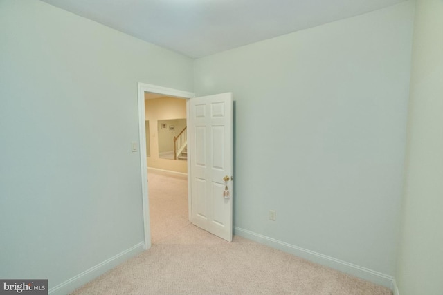 spare room with light colored carpet and baseboards