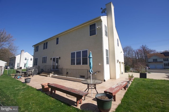 rear view of property featuring a patio, a lawn, and stucco siding