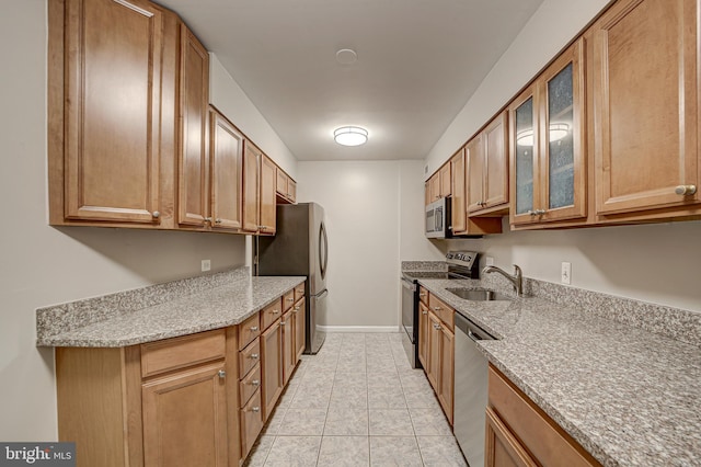 kitchen featuring light stone countertops, light tile patterned flooring, a sink, glass insert cabinets, and appliances with stainless steel finishes