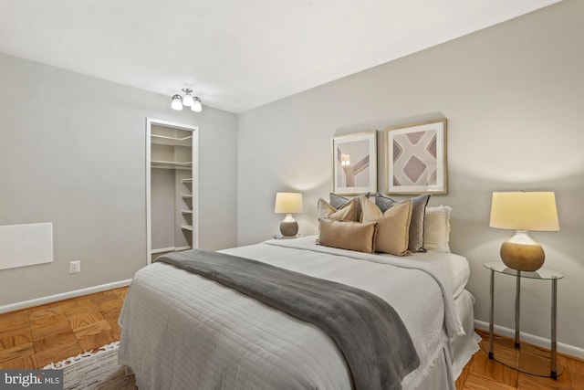 bedroom with a spacious closet, a closet, and baseboards