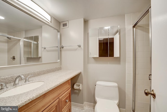 full bathroom featuring visible vents, baseboards, toilet, a tile shower, and vanity