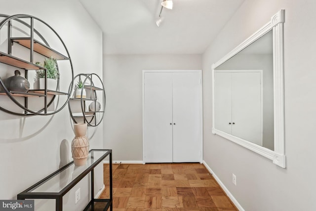 hall featuring track lighting and baseboards