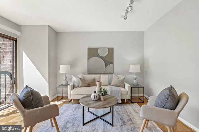 living area with track lighting, baseboards, and wood finished floors